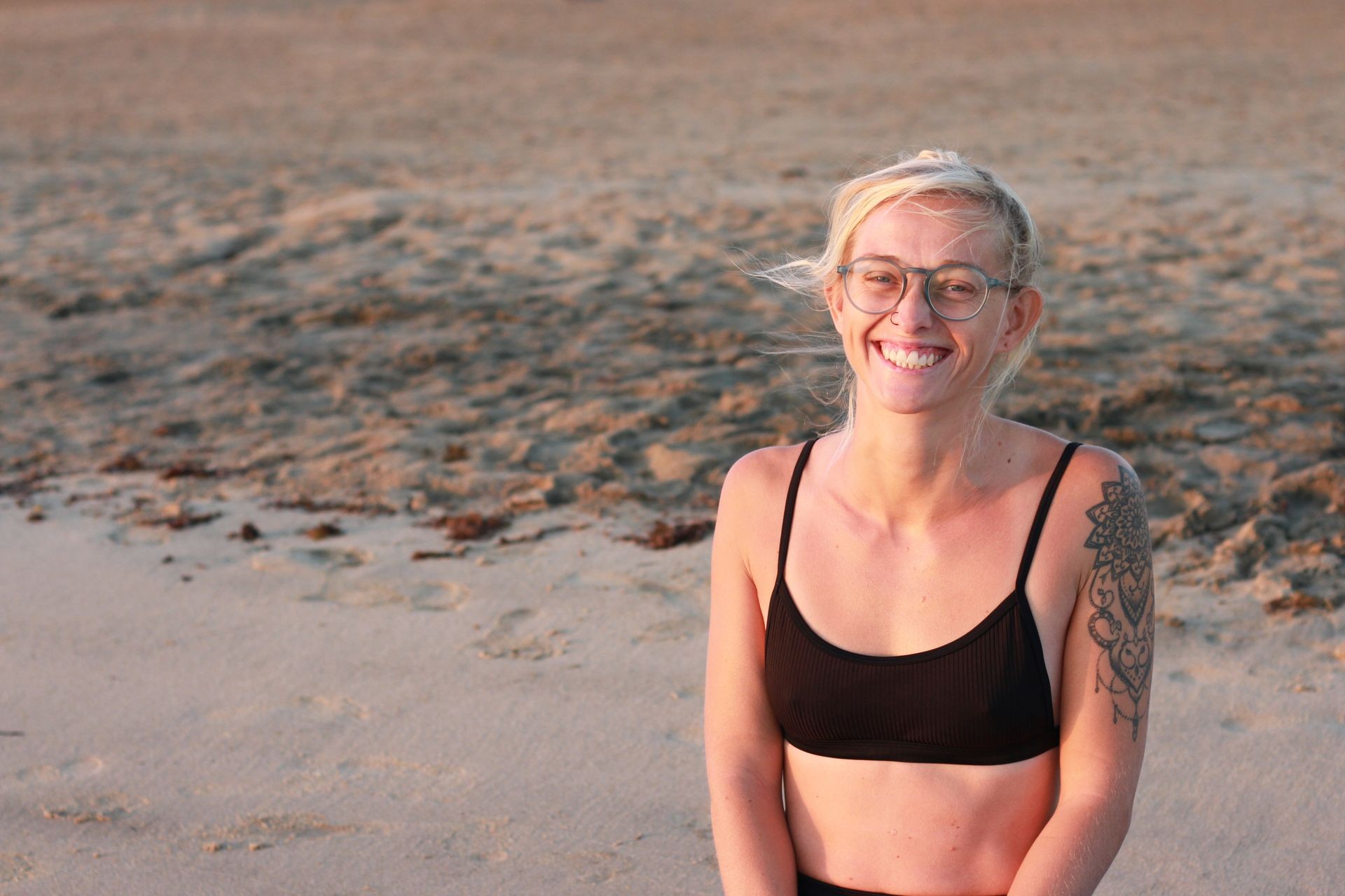 A yogateacher at the beach with a smile. 